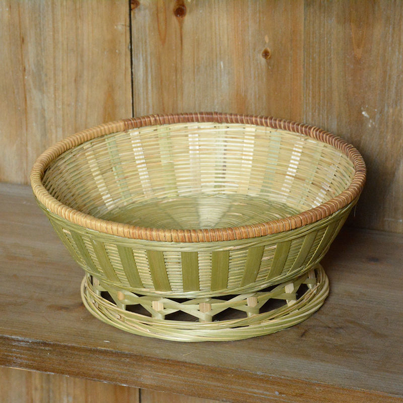 Bau Storage Basket — Shallow round bamboo basket with a green rim.