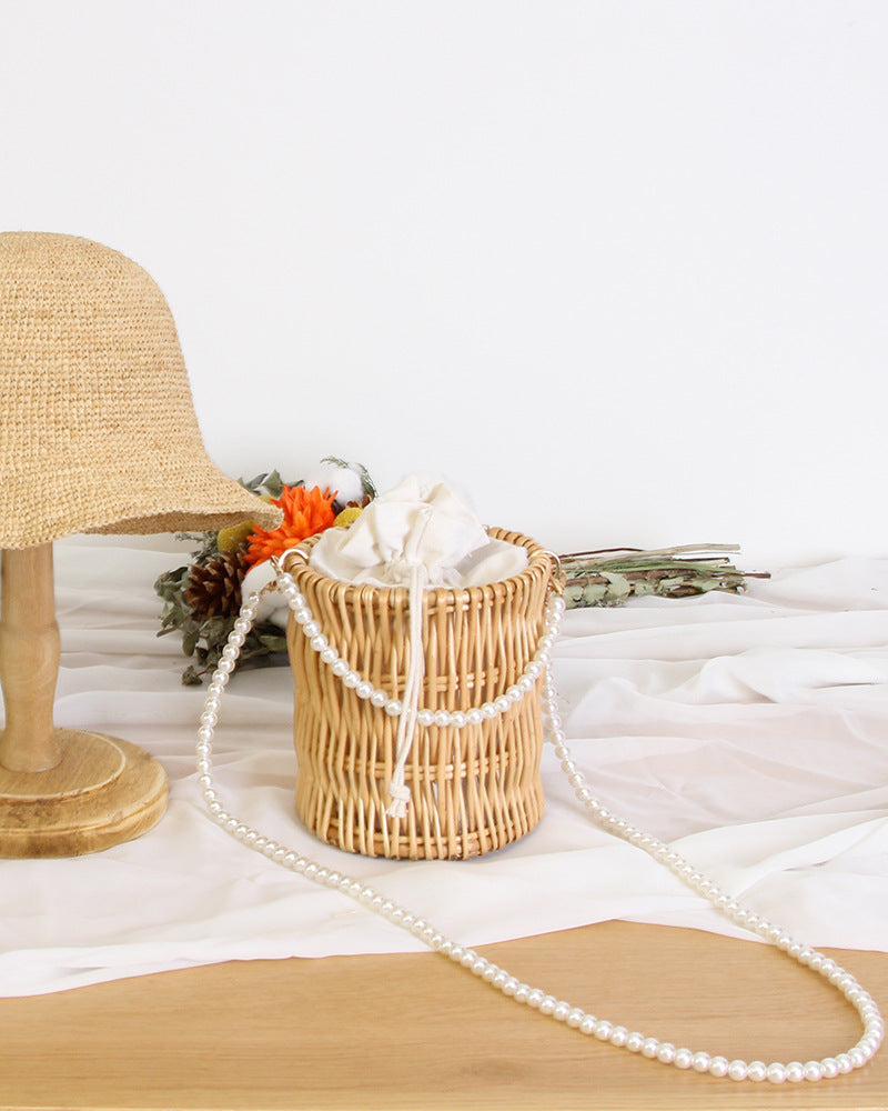 Hualing Woven Crossbody Bag — Cylindrical woven bucket bag with a pearl-style strap.